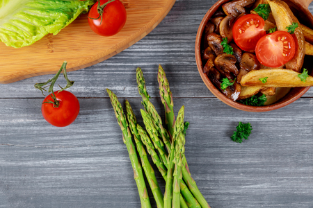 Fried french potato with mushrooms fresh asparagus bunch and tomatoesの写真素材