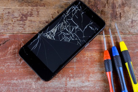Smart phone repair with screwdriver with broken screenの写真素材