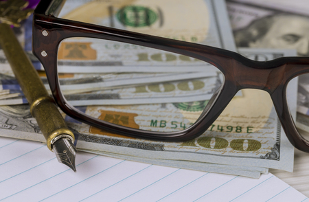 Notebook with hundred dollar bills, pen and glasses financial business accountingの写真素材