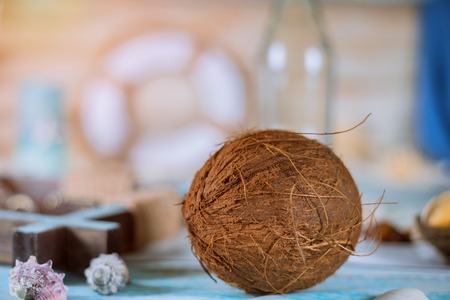 Summer sea shells bottle and coconut on a blue plank backgroundの写真素材