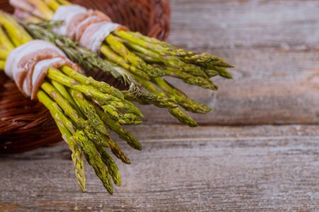 Preparing delicious organic asparagus rolls on bacon wooden tableの写真素材