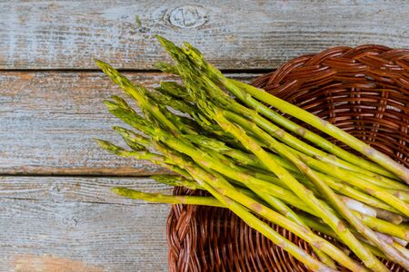 Fresh asparagus in brown basket on wood rustic table.の写真素材