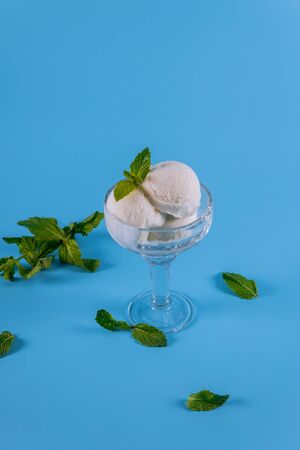 Vanilla ice cream with mint in a glass closeup on blue background.の写真素材