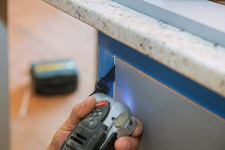 Furniture cutting oscillating multi function power tool on kitchen cabinets framing