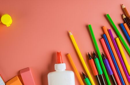 School supplies colored pencils top border on a light pink background