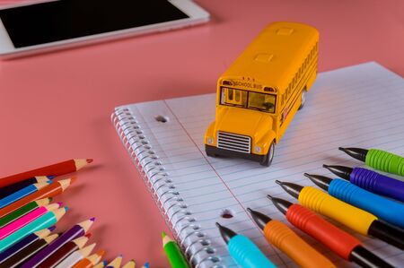 Back to school concept, yellow toy school bus on notebook and pencilsの写真素材