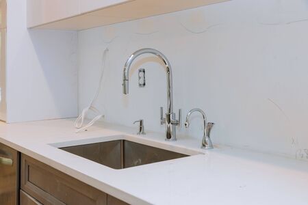 Close up of sinks in modern white kitchen with in designed luxury apartment white stone