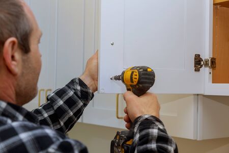 The installing a furniture handle process of assembling kitchen cabinetの写真素材