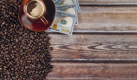 American dollars and coffee beans and coffee cup on a wooden table background.の写真素材