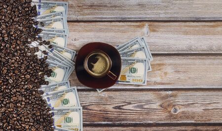 Dollars covered with coffee beans and coffee cup on wooden backgroundの写真素材