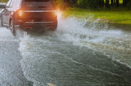 Cars float on water, flooding streets. spraying water of a car moving driving car on flooded road during flood caused by torrential rains.の写真素材