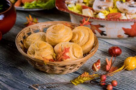 Swirl buns on wicker basket with autumn decoration on table.