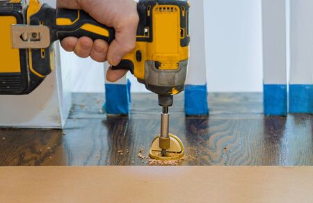 Metal modern professional installing door stopper on wooden floor in using screwdriver
