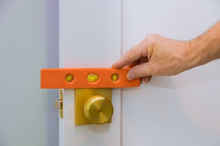 Male carpenter fixing lock in door with home hand close-up.
