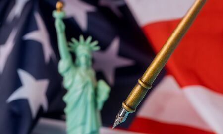 Fountain pen on an Usa American flag stars and stripes on statue of liberty soft focusの写真素材