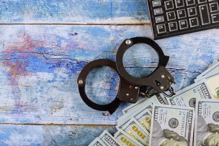 Financial crime accounting, US dollar banknotes money cash corruption money and calculator metal police handcuffsの写真素材