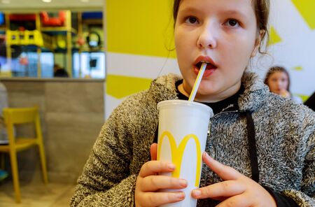 NewYork NY NOV 07 2019: Young girl drinks Coca-Cola at McDonald's restaurant.