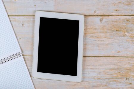 Workspace desk with paper notebook on table touch screen device with copy space wood backgroundの写真素材