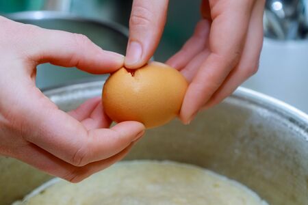 Cook breaking egg into the bowl in a bakery