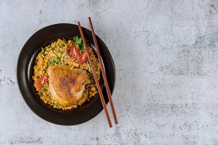 Fried pasta and rice chicken with parsley and tomatoes with chopsticksの写真素材