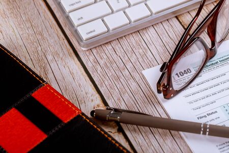 Workplace in the accountant's office desk table U.S. income tax 1040 form with glasses and pen on...