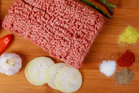 Raw minced meat beef with various spices and notebook and pen on a wooden board