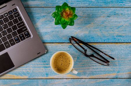 Workspace with office table with computer and coffee cup, glasses view from above.