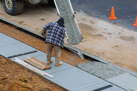 Pouring cement in process of pouring concrete into newly paved sidewalk
