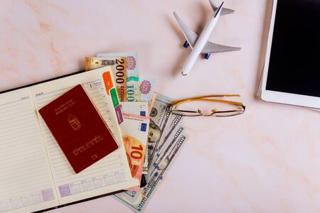 Travel booking flights reservation on the devices tablet touch pad with Hungarian passports and dollar banknotes Planning a tripの写真素材
