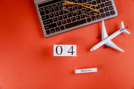04 January calendar with accessories on business workspace office desk on computer keyboard, airplane, glasses on red desk backgroundの写真素材