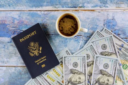 US passport with dollar bill and cup of coffee on blue wooden table.の写真素材