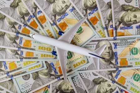 Background of one hundred dollar bills with model airplane on flat lay design to travel concept