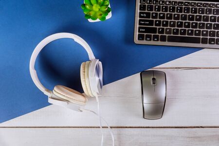 office computer keyboard lying on a white headphones with office work placeの写真素材
