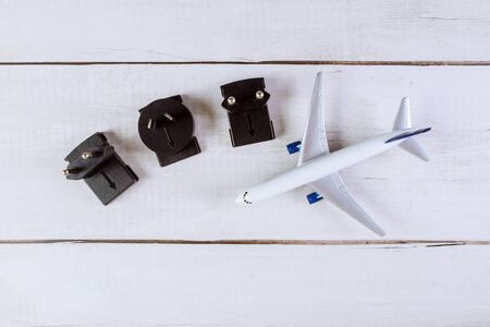 Universal electric socket plug adapters used for travel flat lay of white model plane, airplane