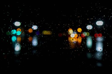 Wet the window with night rain and town lights night city background