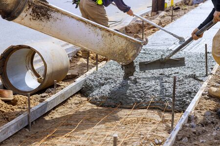 Truck loads of concrete pouring at construction into the concrete at a construction in a sidewalk