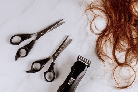 Professional hairdresser scissors on electric hair clipper with brown female hairの写真素材
