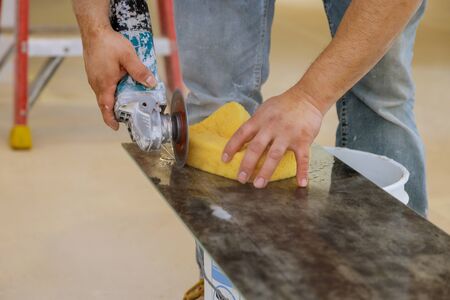 Worker in uses grinder for cutting tiles porcelain stoneware work trimming tiles