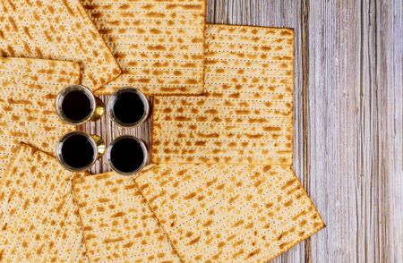 Passover matzoh jewish holiday bread and four glasses kosher wine over wooden table background.の写真素材