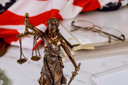 Law judge desk with Lady Justice Statue on of paper files documents stacked with US flag, judge's officeの写真素材