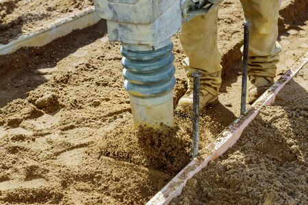 Construction process in the during sidewalk on vibrating hammer, with sand jumpingの写真素材