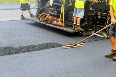 Asphalting paver machine during road construction of the road with asphalt
