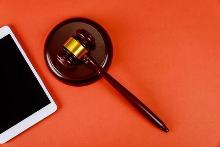 Workspace for lawyer with digital tablet blank screen and judges wooden gavel on red backgroundの写真素材