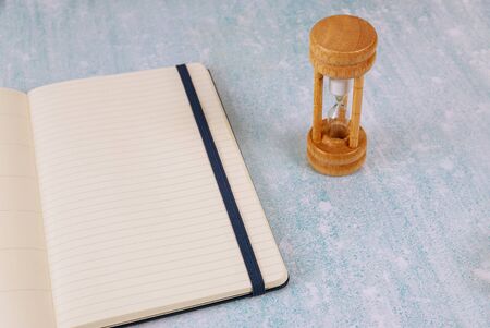 Concept for business deadline hourglass as time passing with notepadの写真素材