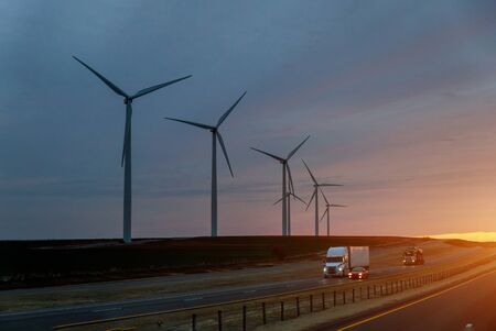 Road Leading to view of the Texas wind turbine farms in the beautiful sky during sunset showingの写真素材