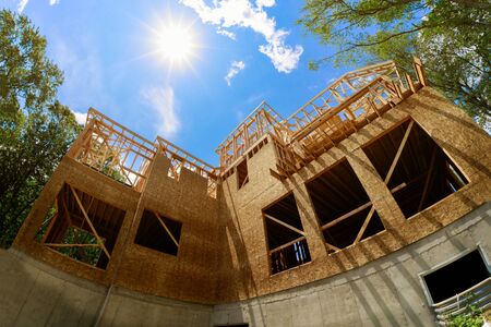 A roof on beam, built new home residential construction house framing against a blue sky