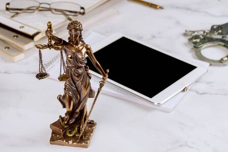 Lawyer Statue of Justice with scales lawyers symbols office working on a digital tabletの写真素材