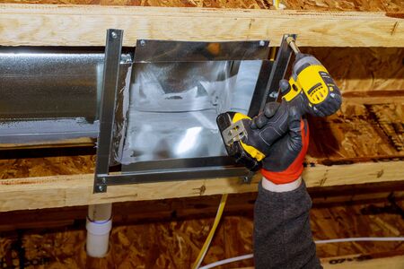 Worker installing new air conditioner vents in new home construction