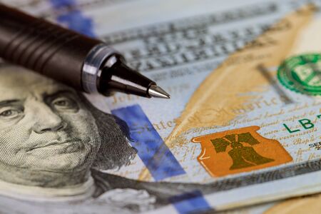 Close-up tax concept pen and 100 US dollar bills background