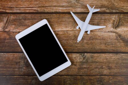 Summer holiday on wooden table background travel concept with using digital tablet airplane model planeの写真素材